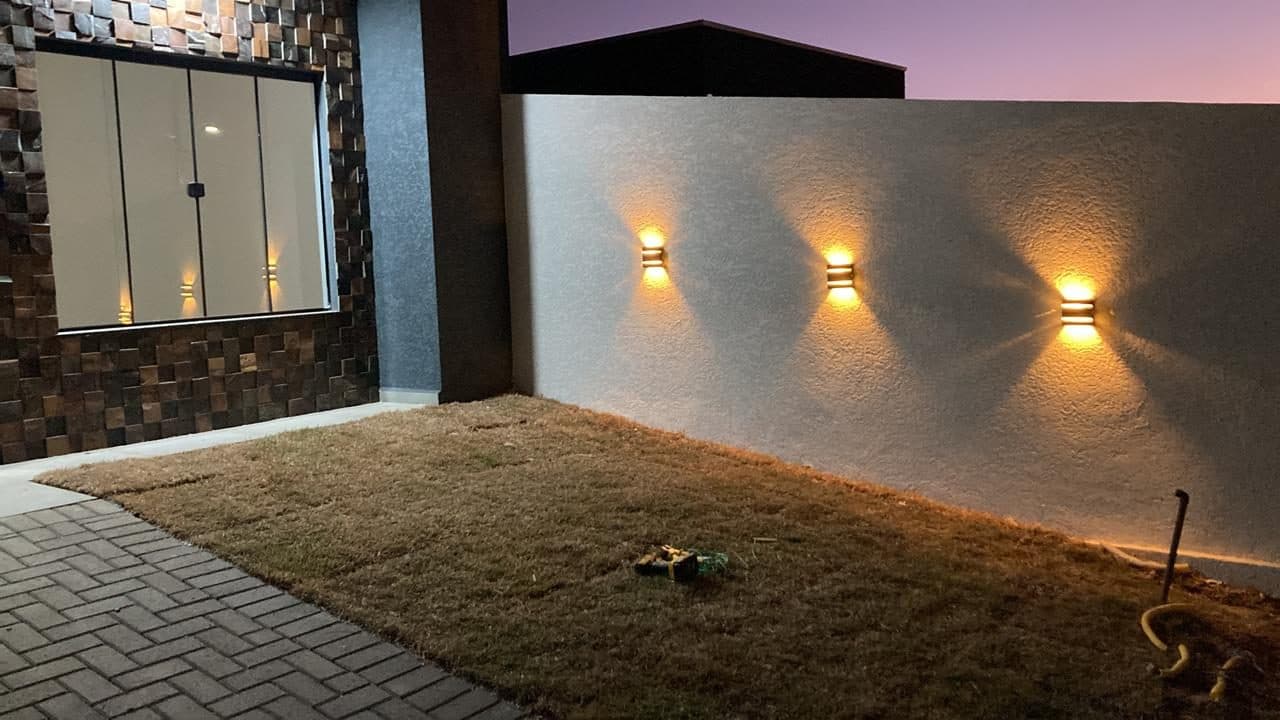 Quintal de casa do Cidade Jardim ao anoitecer, com arandelas externas acesas