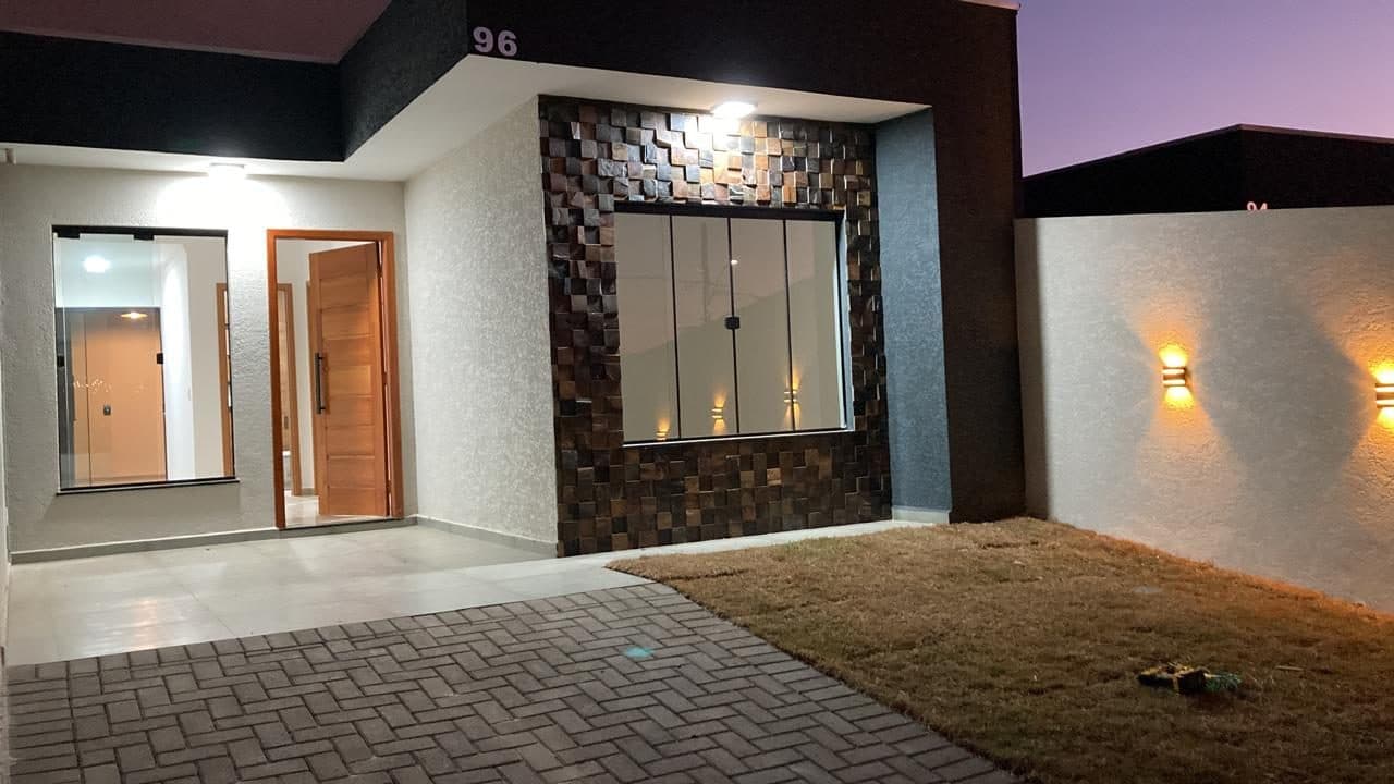 Fachada de casa entregue do Cidade Jardim à noite, com pedra ferro e arandelas acesas