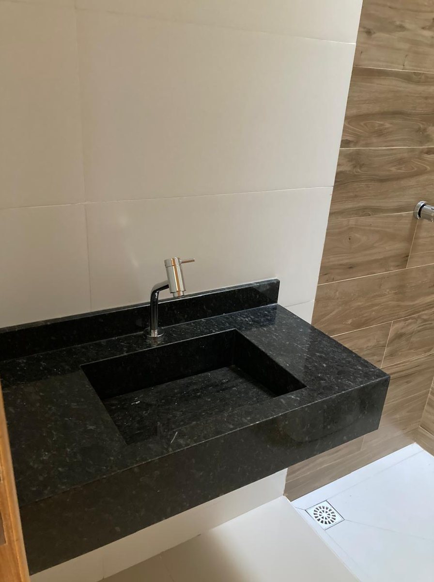 Banheiro de casa entregue, com bancada em granito, cuba esculpida e parede em porcelanato amadeirado