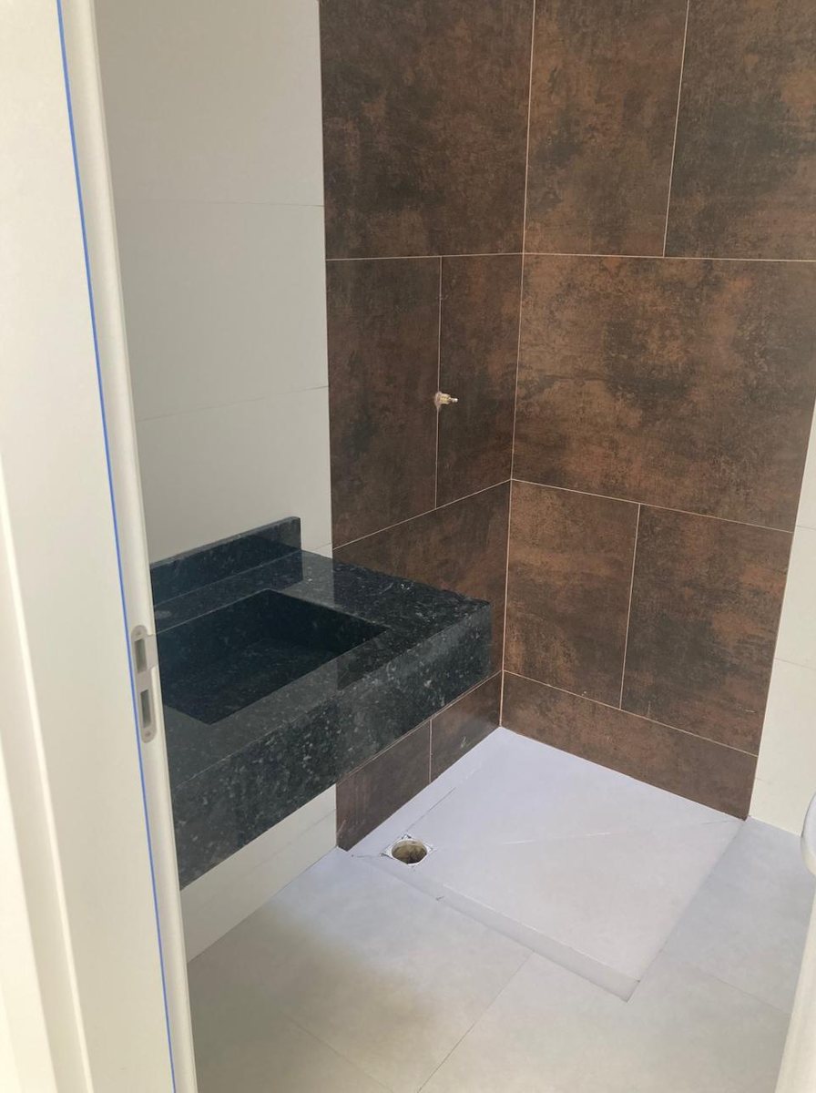 Box de banheiro de casa entregue, revestido em porcelanato marmorizado, com bancada em granito
