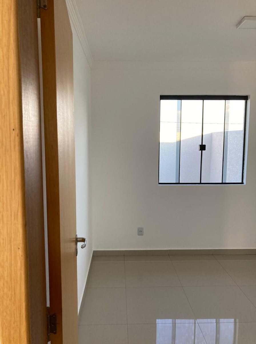 Quarto de casa entregue, com porcelanato no piso, porta de madeira e janela